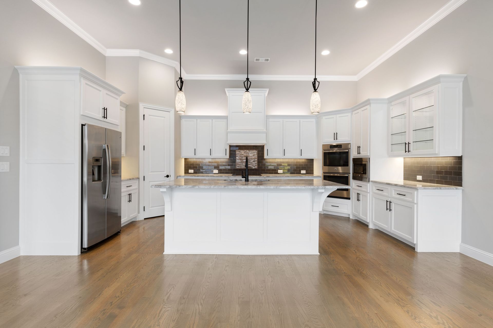 A large kitchen with white cabinets , stainless steel appliances