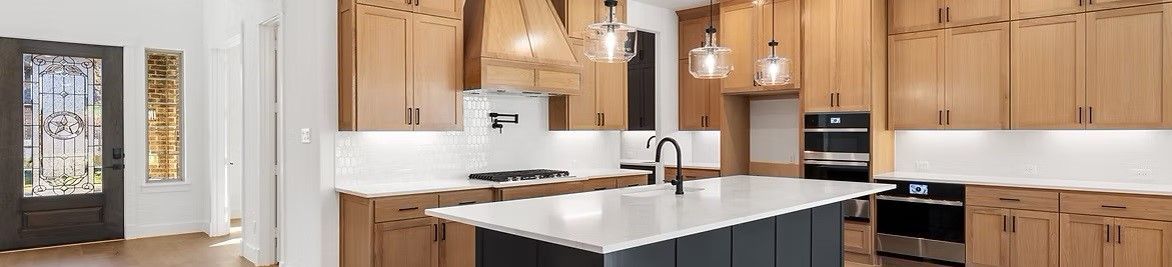 A kitchen with wooden cabinets and a large island in the middle.