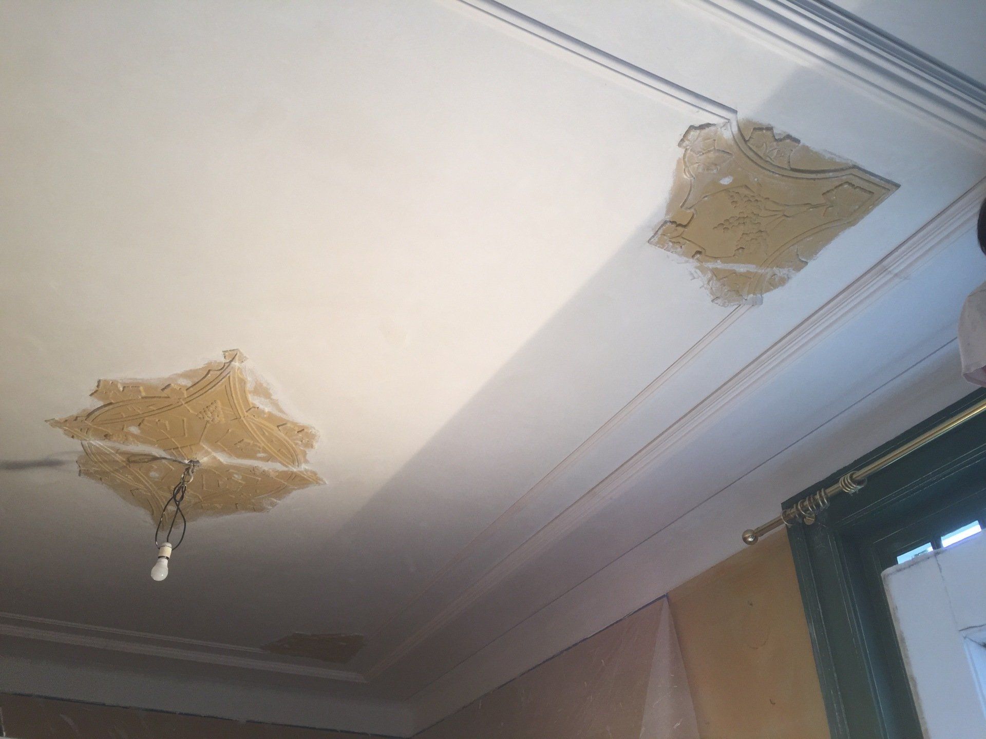 Een gerestaureerd plafond met opgeknapte ornamenten en nieuwe lijsten.