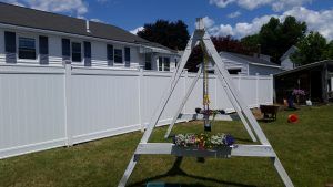Tall fence with flowers in the foreground and a shed in the background