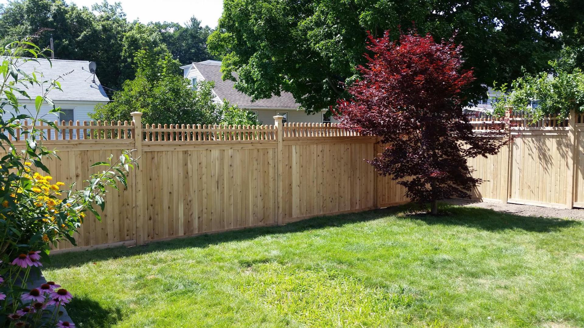 Wooden fence with intricate details surrounding a property and garden in Concord, NH