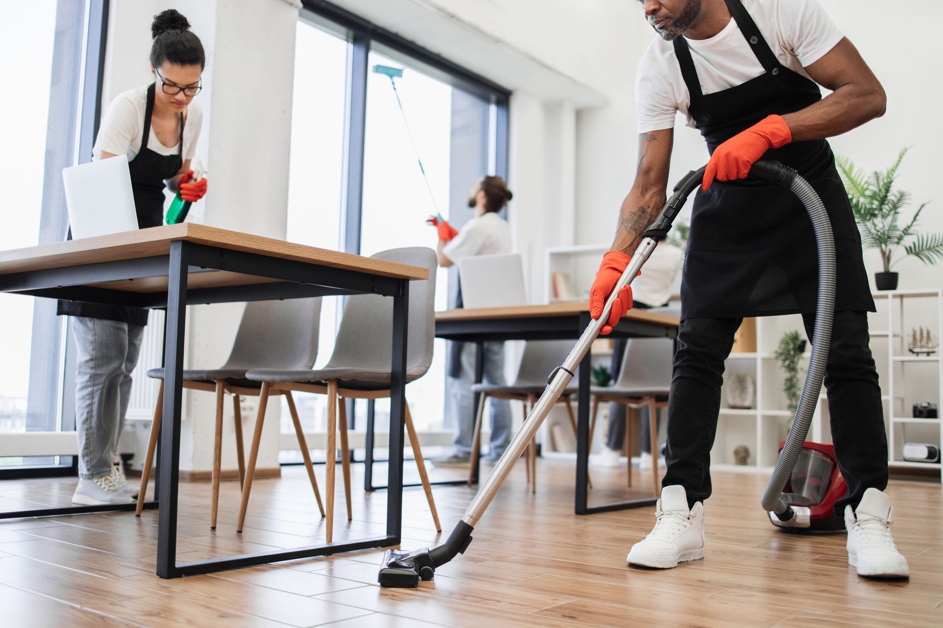 Cleaning crew vacuuming and dusting an office, wearing aprons and gloves. Cleaning crew vacuuming and dusting an office, wearing aprons and gloves.