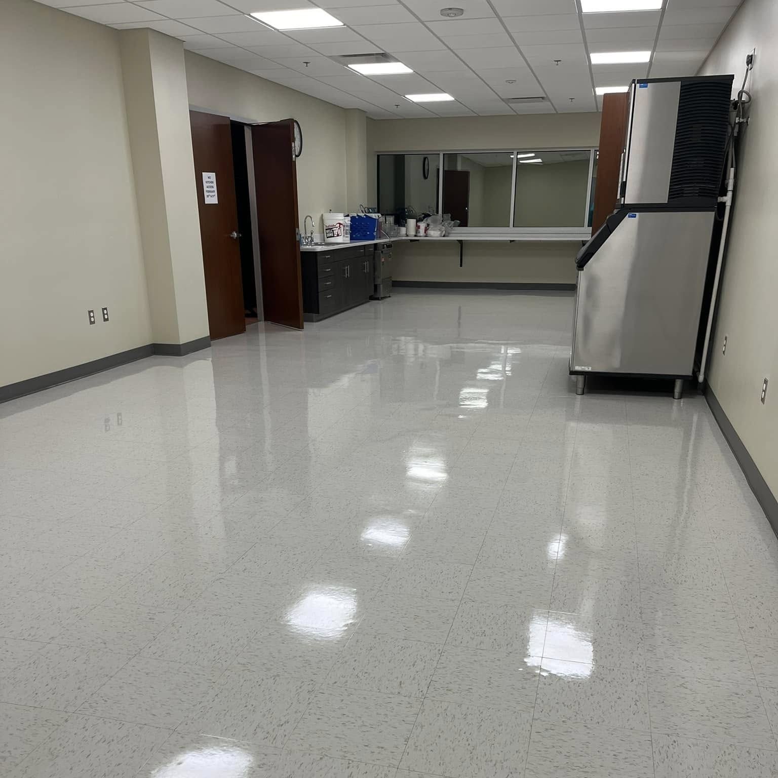 Empty, brightly lit room with shiny gray floor and an ice machine.