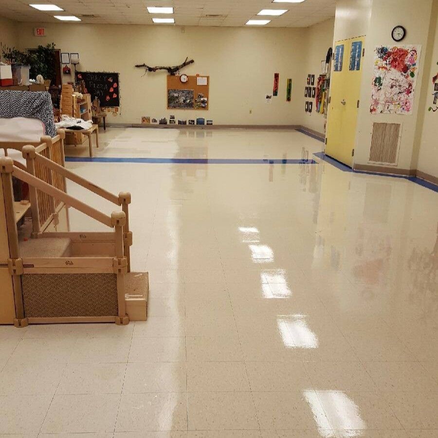 Empty classroom with shiny beige floor, wooden steps, and art on the wall.