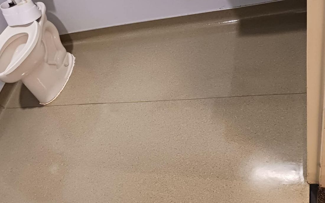 Toilet in a beige bathroom. Floor has a visible crack.