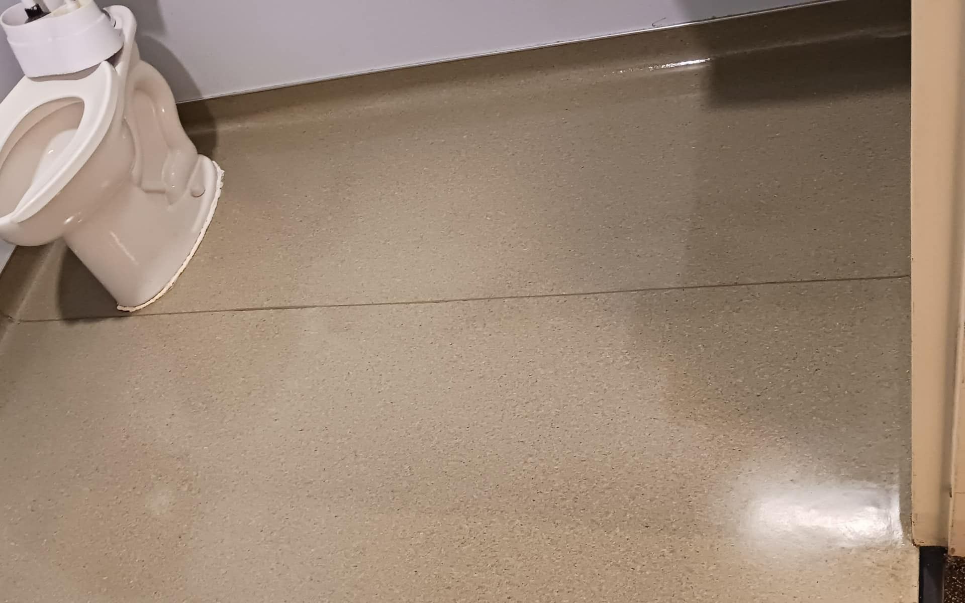 Toilet in a beige bathroom. Floor has a visible crack.