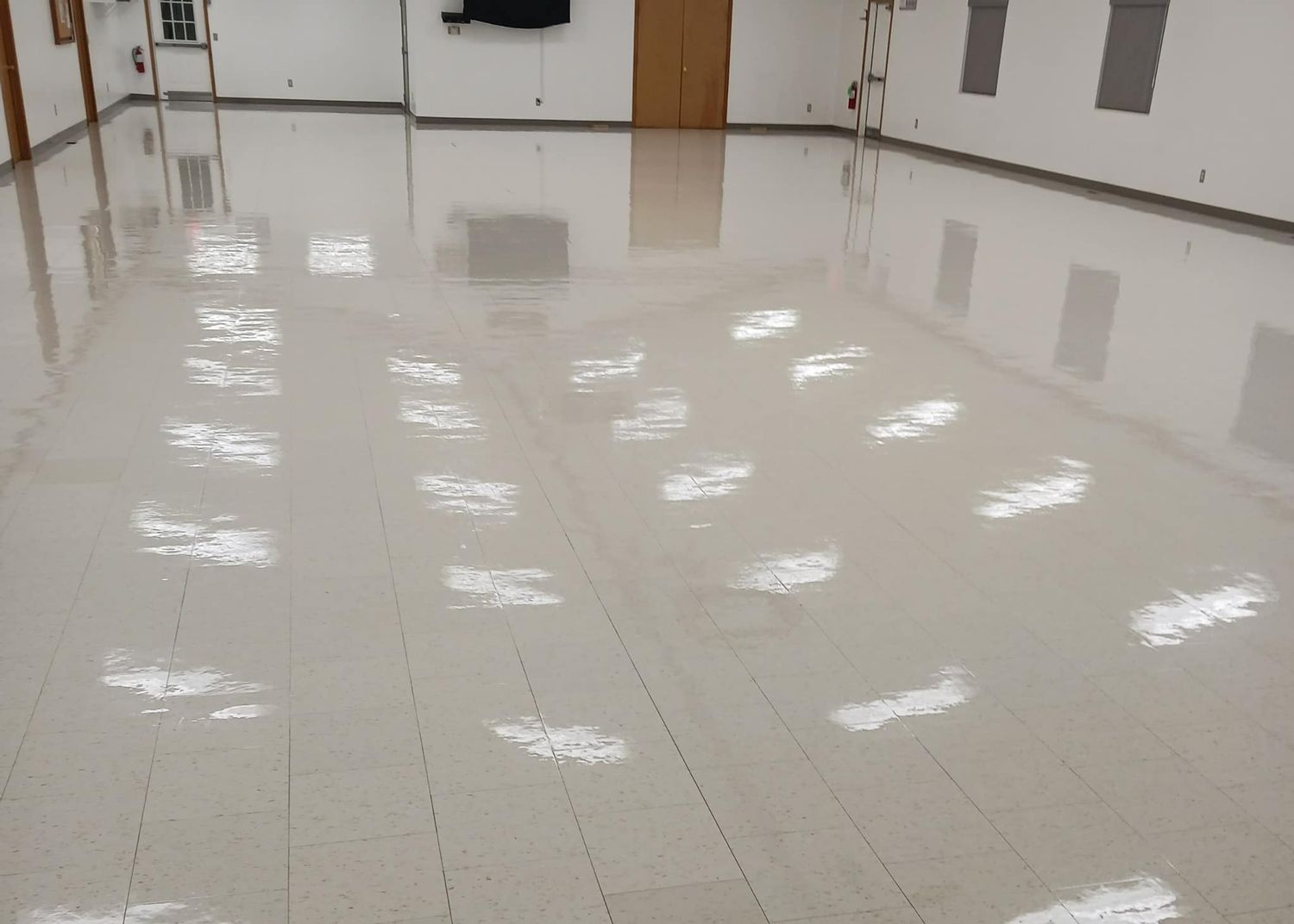 Shiny, light-colored floor reflecting overhead lights in a large, empty room.