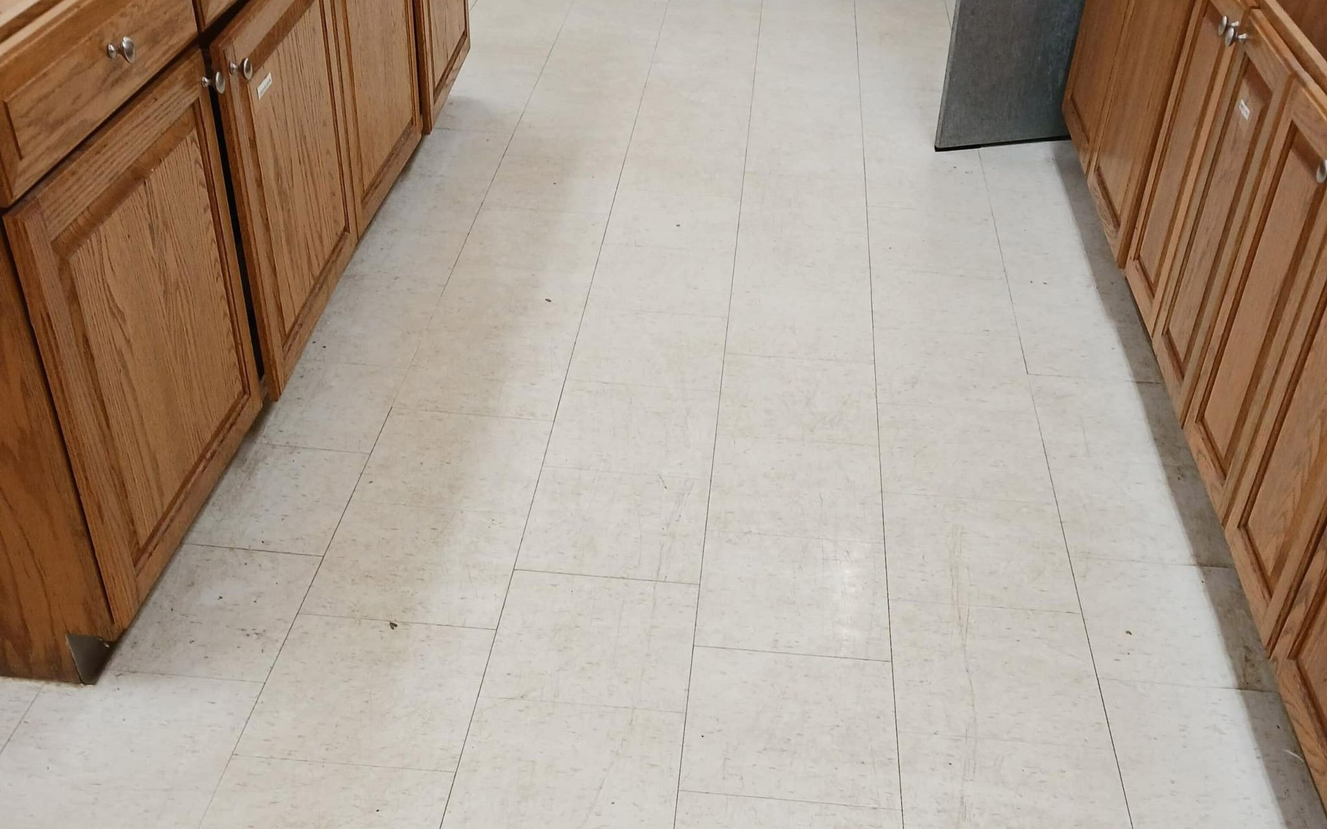Kitchen with beige tile flooring, brown cabinets on both sides.
