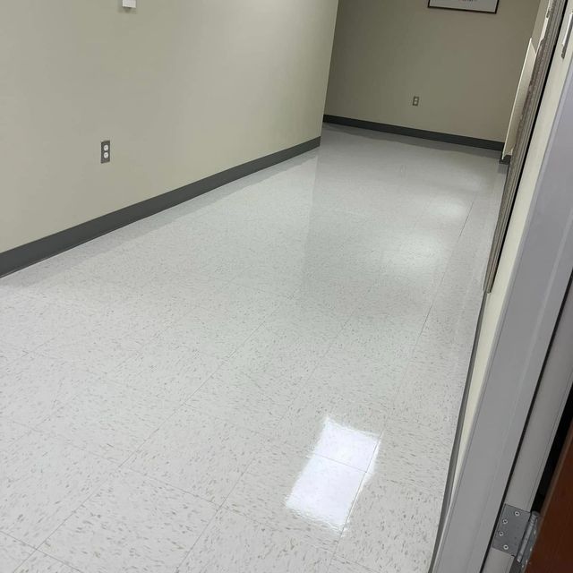 White-tiled hallway with beige walls, gray baseboards, and a partially visible doorway on the right.