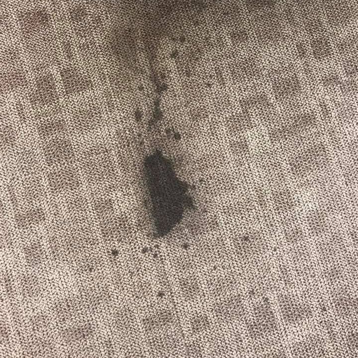 Dark stain on patterned beige carpet.