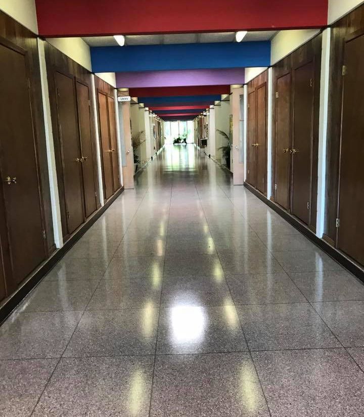 Long hallway with brown doors, shiny floor, and colorful ceiling.