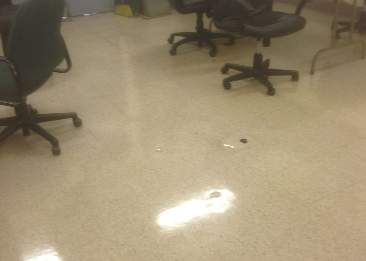 Office floor with chairs; a light stain and a dark spot are visible.