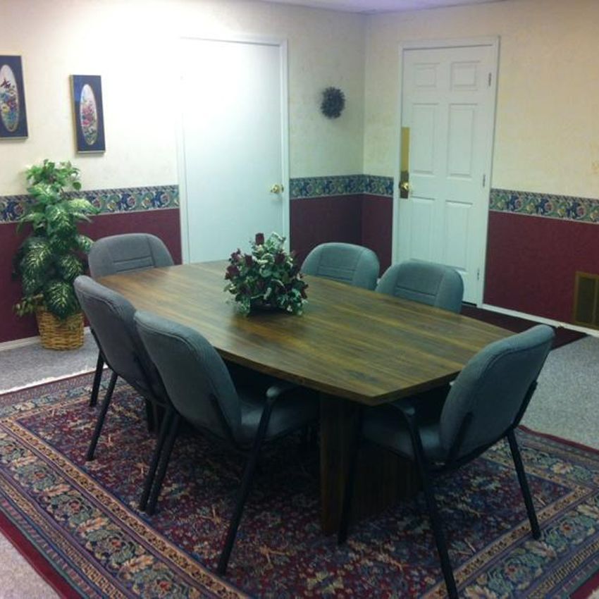 Conference room with a wooden table and chairs, on a patterned rug.