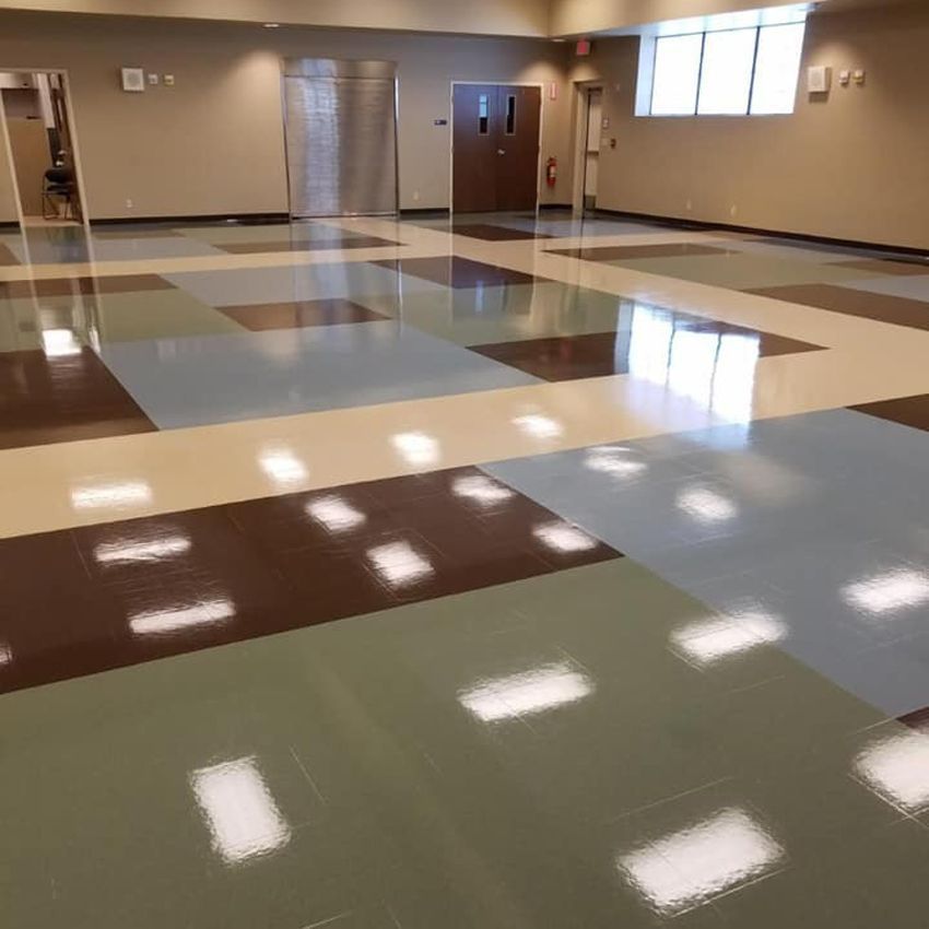 Empty room with patterned floor, tan walls, doors, and windows.