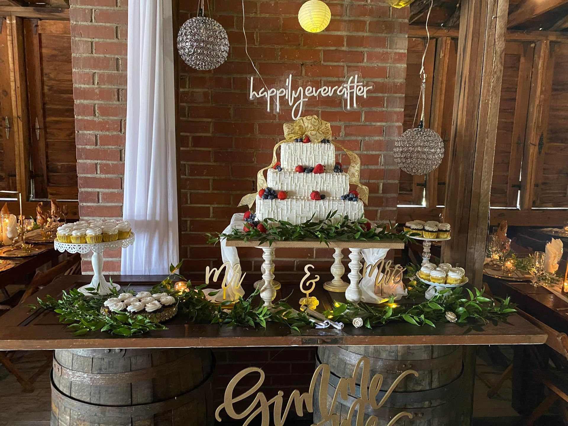 wedding cake and cupcakes surrounded by greenery