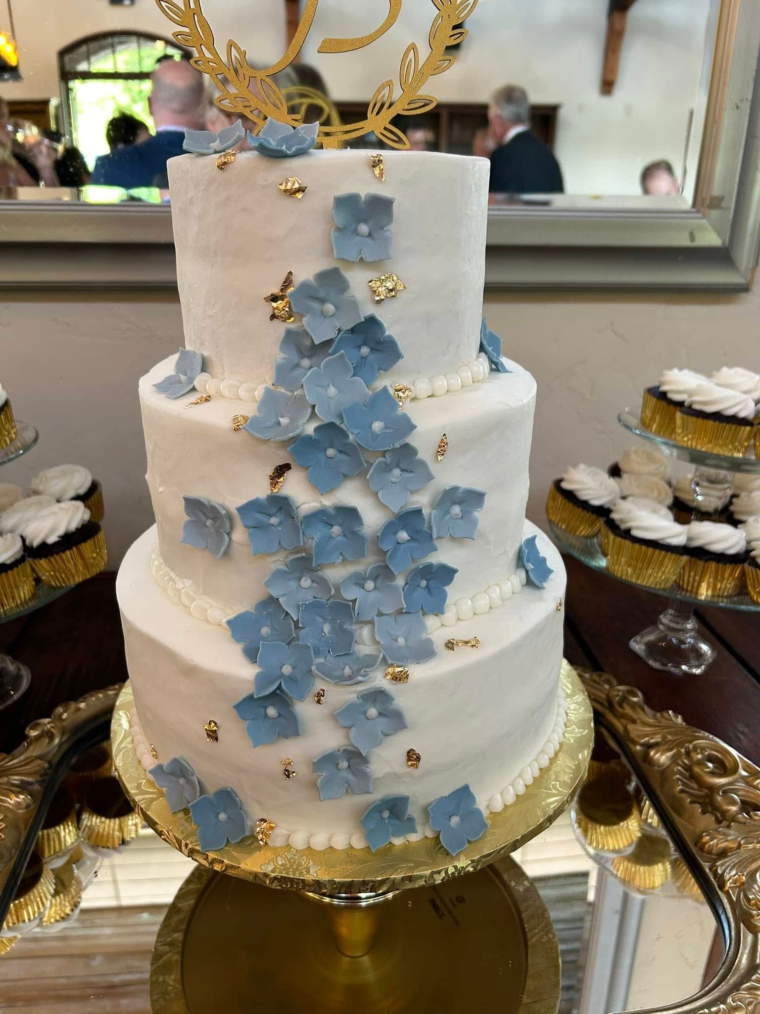 wedding cake with blue iced flowers and gold foil
