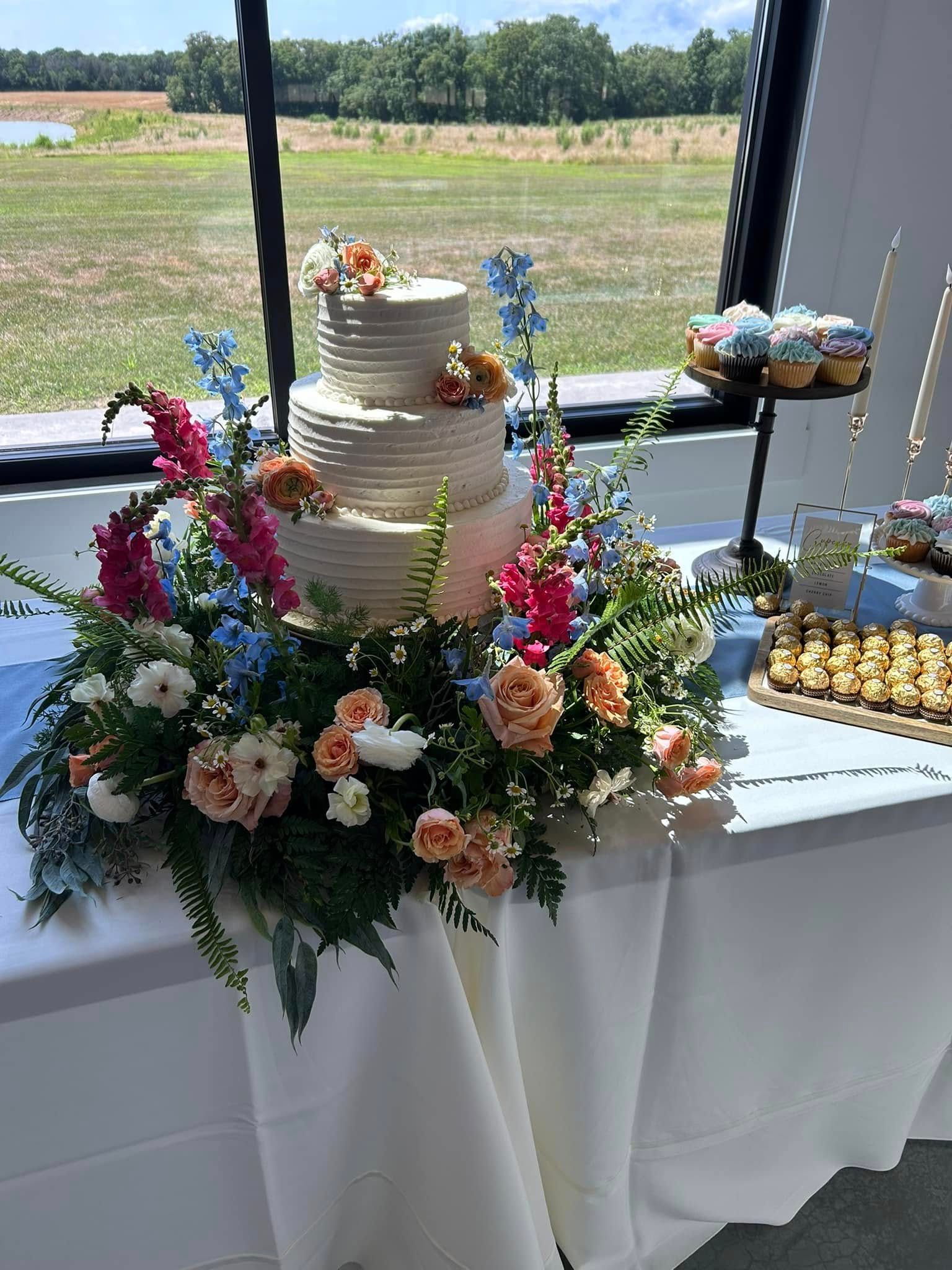 wedding cake surrounded by colorful wedding flowers