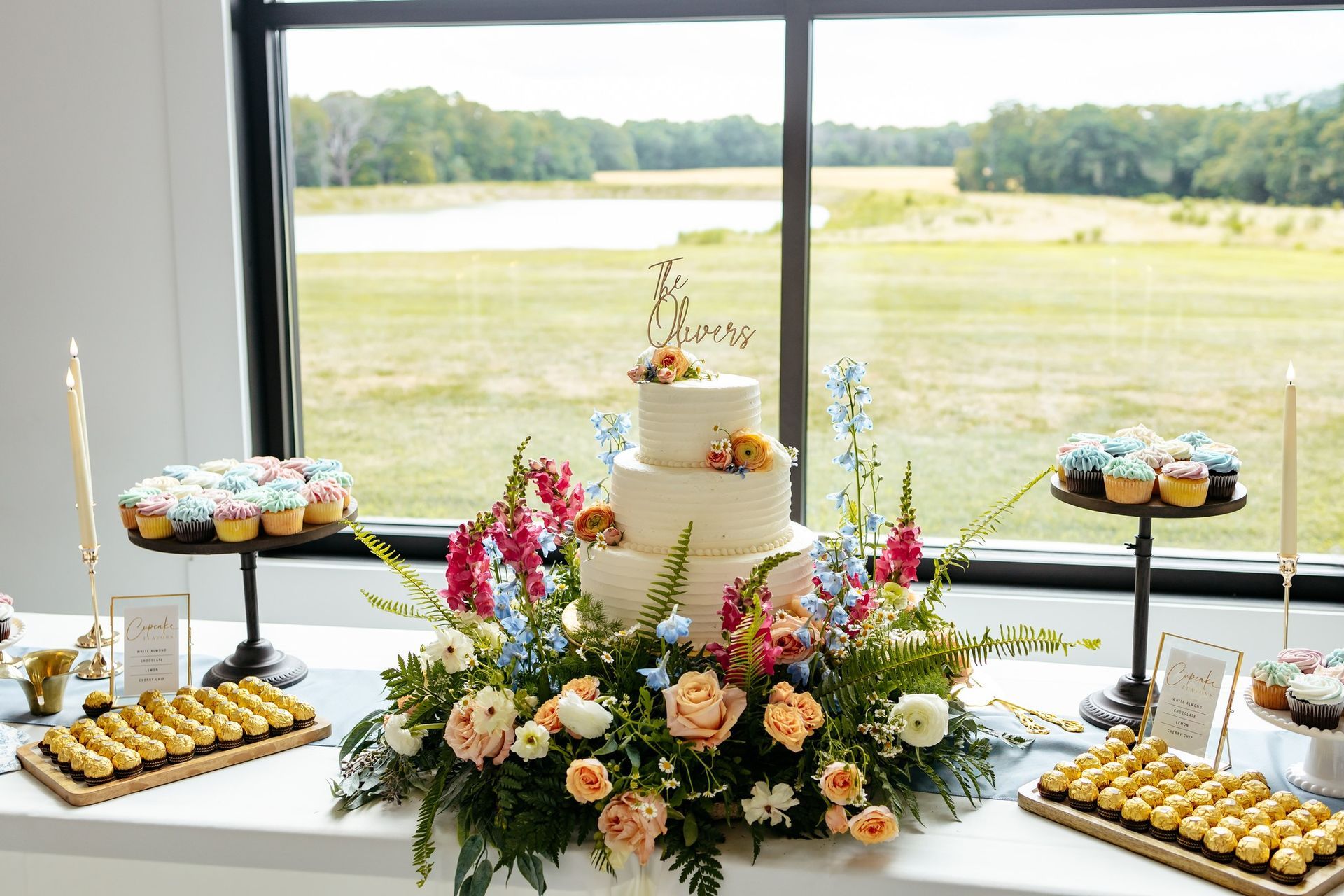 wedding cake and cupcakes surrounded by flowers