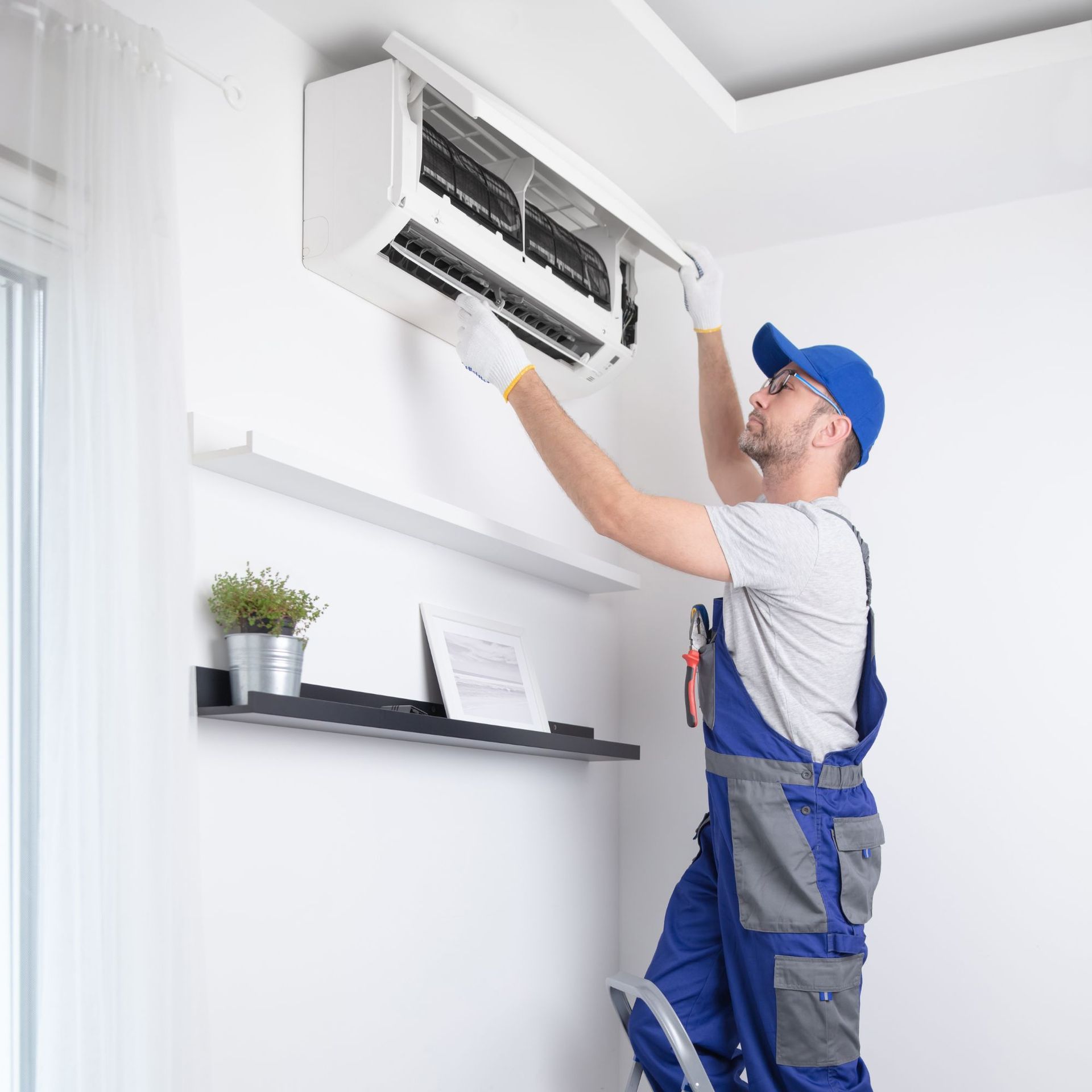 CC Air Services LLC - A man is standing on a ladder fixing an air conditioner.