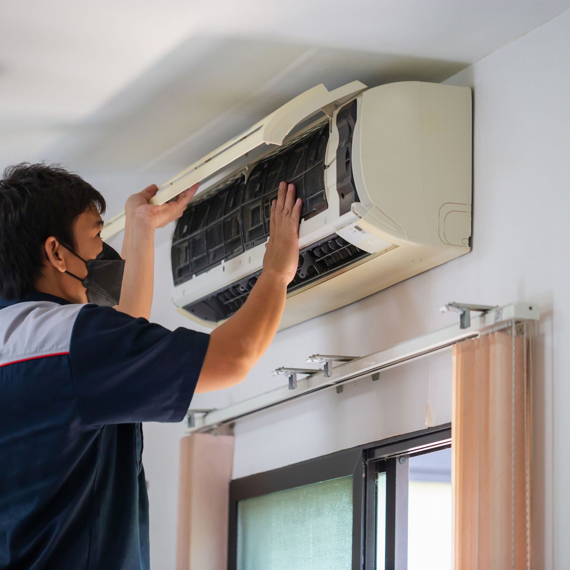 CC Air Services LLC - A man wearing a mask is working on an air conditioner.