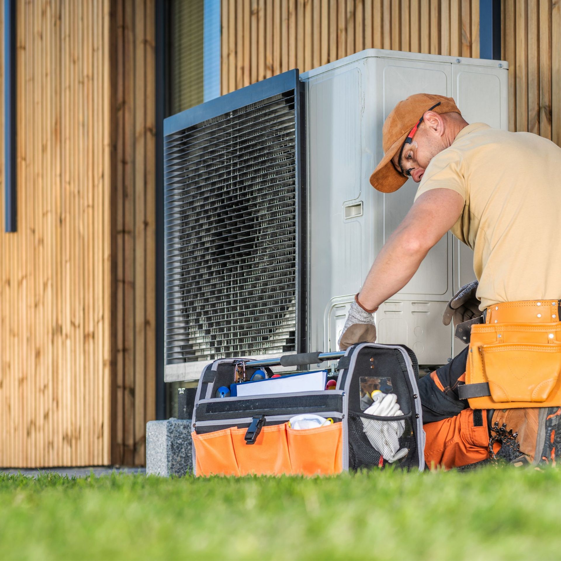 CC Air Services LLC - A man is working on an air conditioner outside of a building.