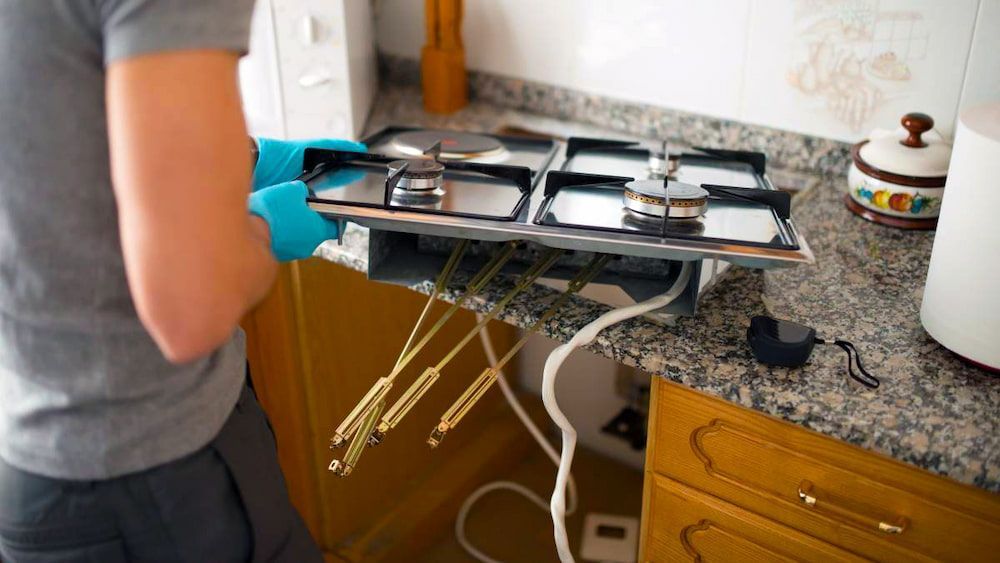 A Man is Holding a Broken Gas Stove in a Kitchen — Darwin’s Gas Man in Marrara, NT