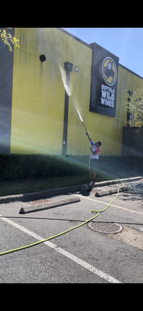 A worker uses a high-pressure hose to clean the exterior yellow wall of a Buffalo Wild Wings restaurant.