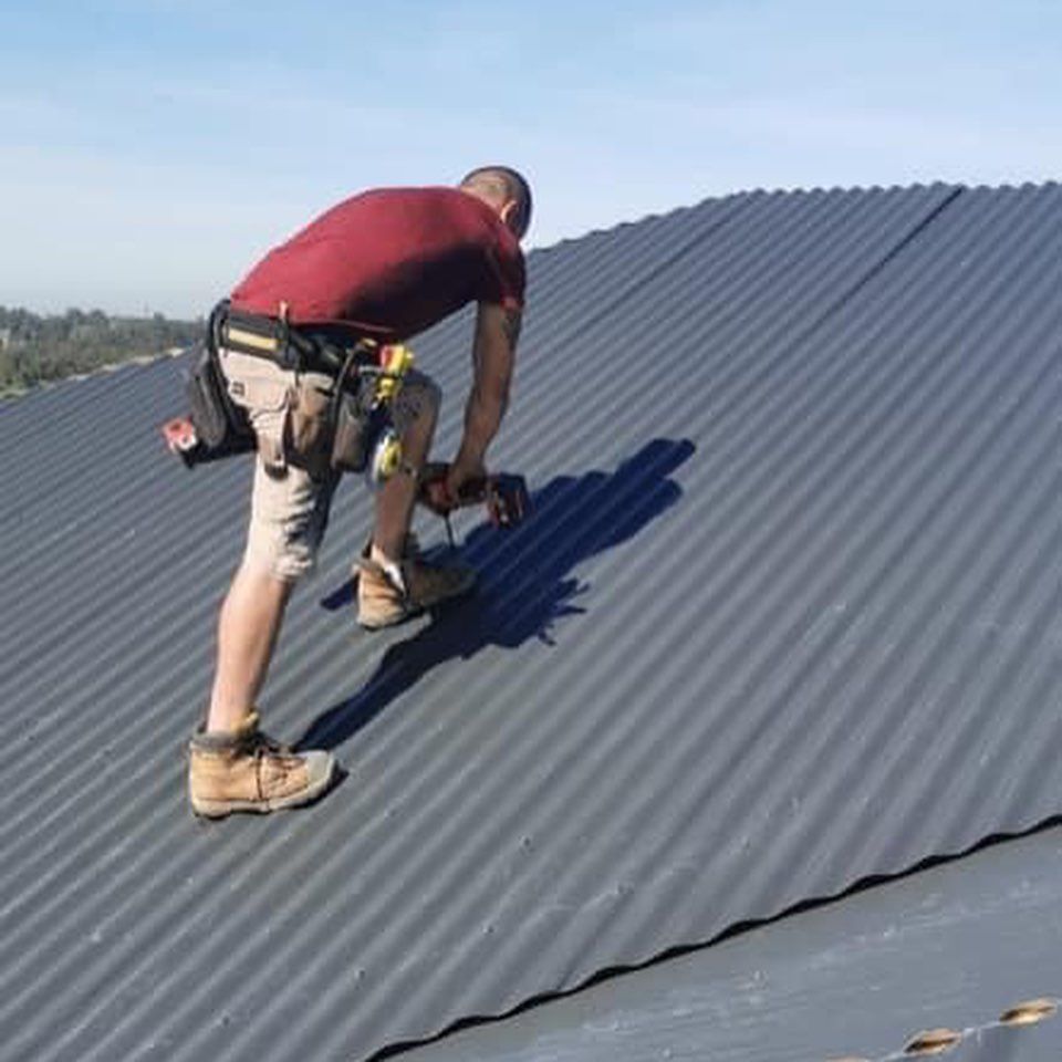 A man is working on a roof with a drill.