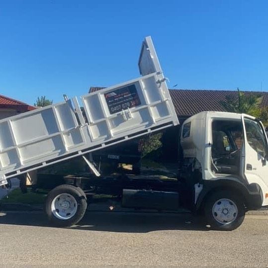 A white dump truck is parked on the side of the road.