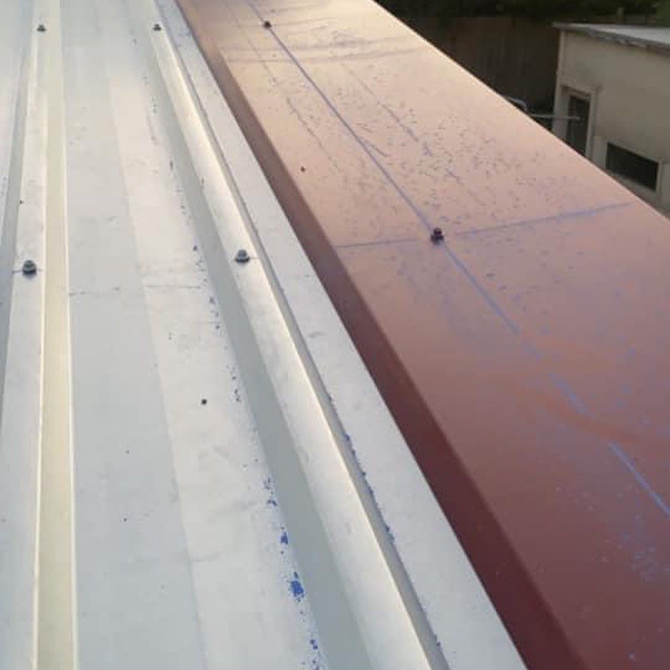 A white roof with a red roof behind it