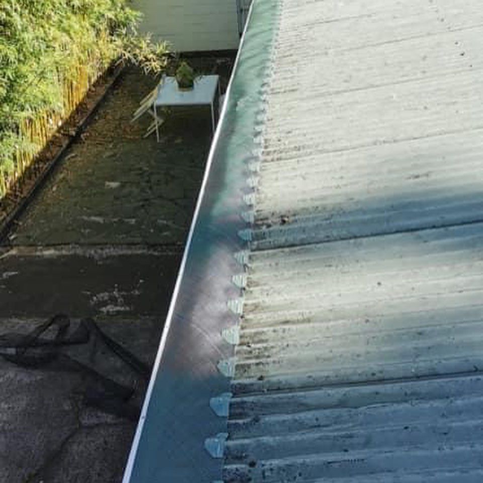 A gutter on the side of a roof next to a table and chairs.