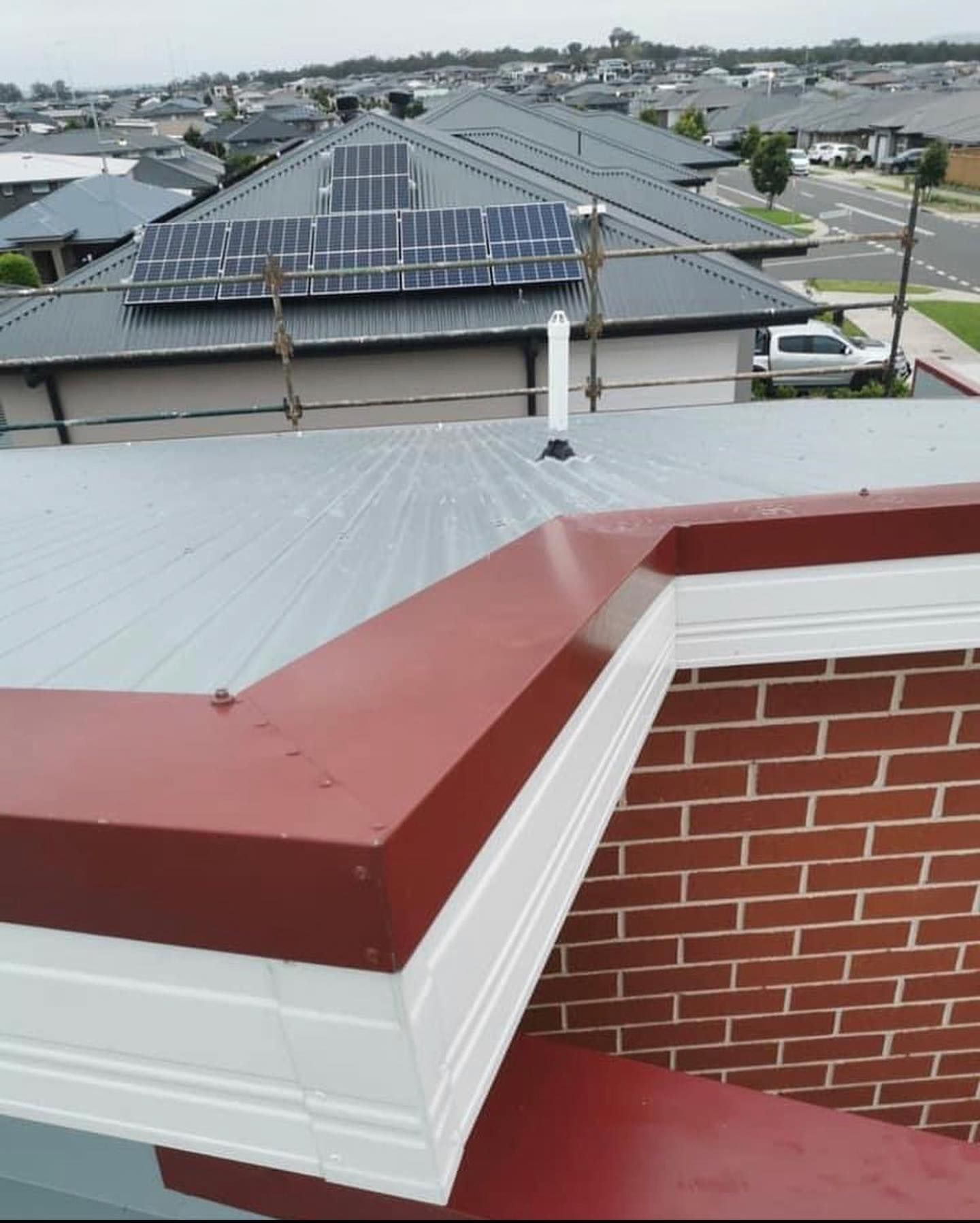 A roof with a brick chimney and solar panels on it