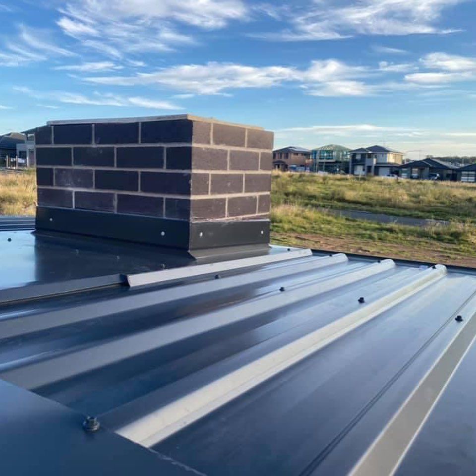 A brick chimney is sitting on top of a metal roof.