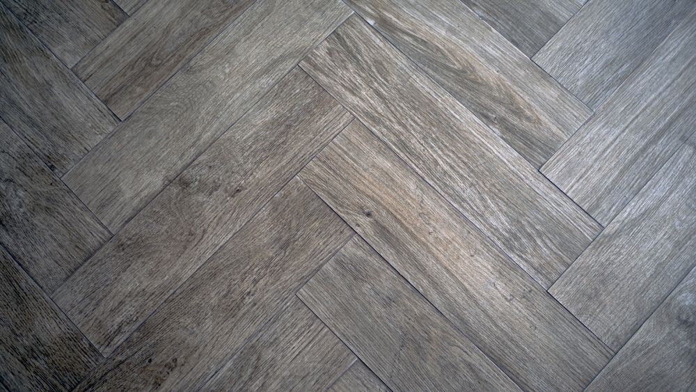 A Close Up Of A Wooden Floor With A Herringbone Pattern — B2B Flooring Solutions In Coffs Harbour, NSW