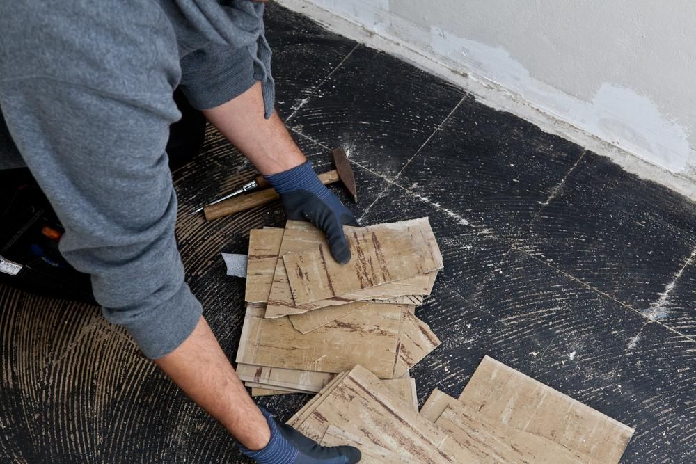 A Man Is Hammering A Piece Of Cardboard On The Floor — B2B Flooring Solutions In Taree, NSW