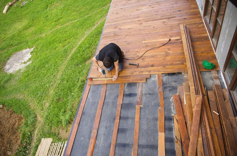 A Man Is Working On A Wooden Deck — B2B Flooring Solutions In Mid North Coast, NSW