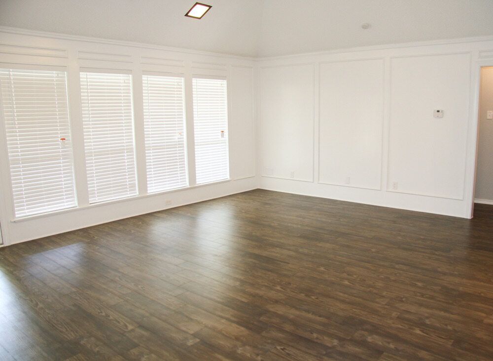 An Empty Living Room With Hardwood Floors And White Walls — B2B Flooring Solutions In Coffs Harbour, NSW