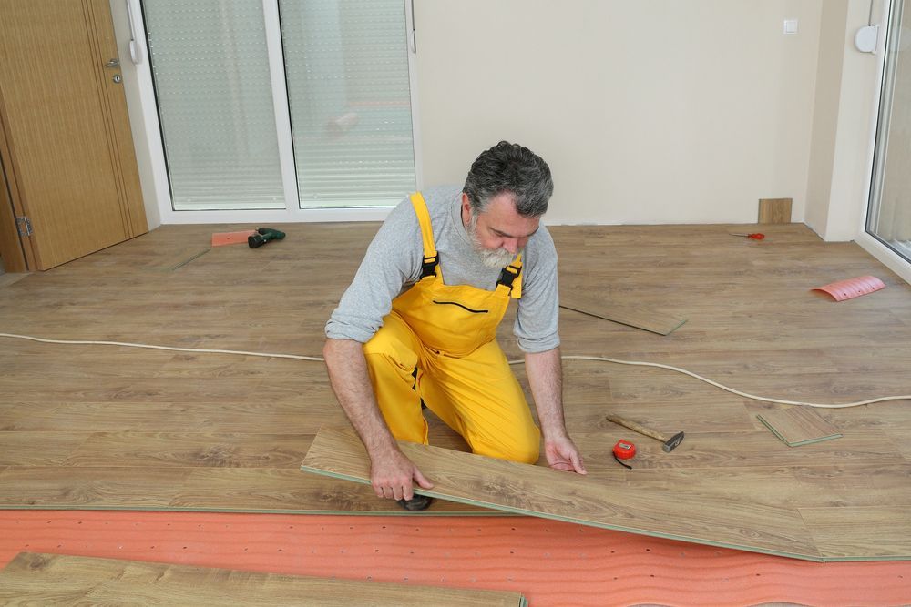 Adult Male Worker Installing Laminate Floor, Floating Wood Tile — B2B Flooring Solutions In Coffs Harbour, NSW
