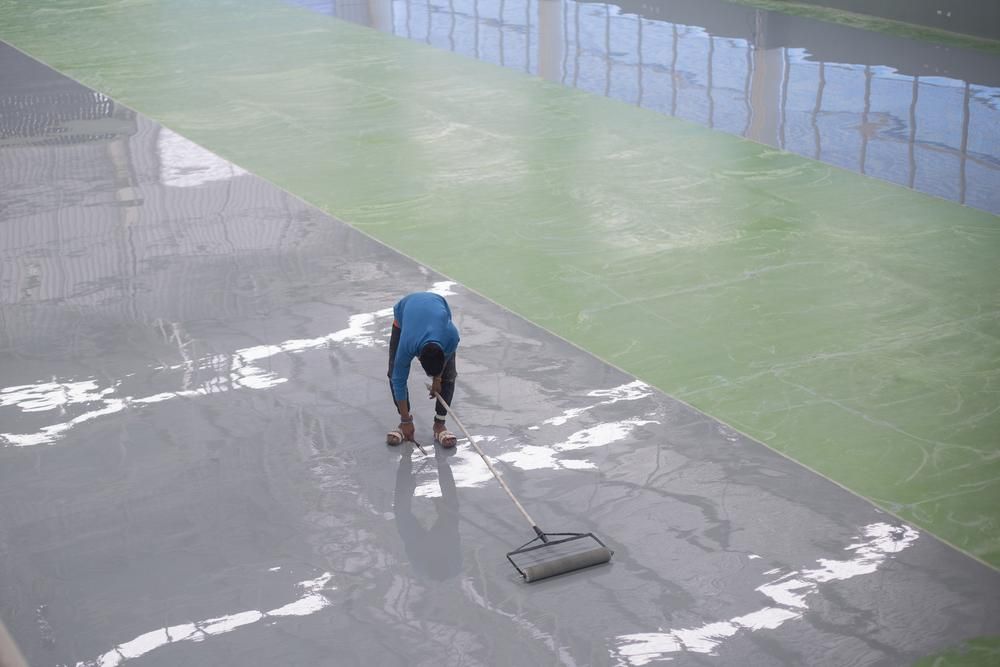 A Man Is Cleaning The Floor Of A Building With A Broom — B2B Flooring Solutions In Clarence Valley, NSW