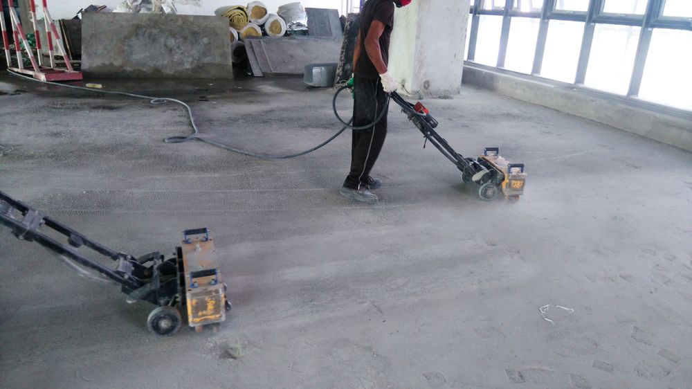 A Man Is Using A Machine To Clean A Concrete Floor — B2B Flooring Solutions In Yamba, NSW