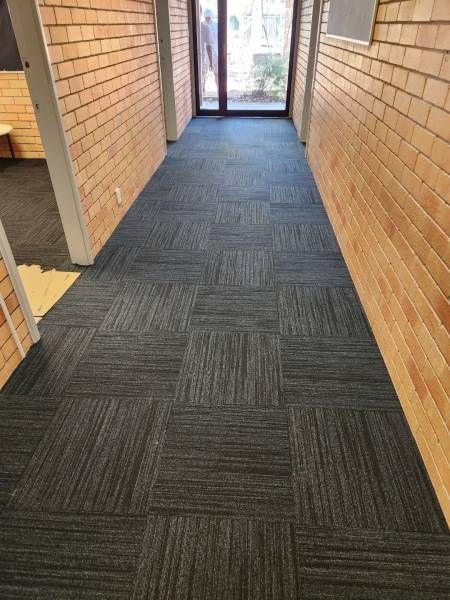 A Long Hallway With A Black Carpet And Brick Walls — B2B Flooring Solutions In Coffs Harbour, NSW