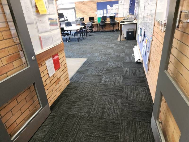 A Hallway In A Classroom With A Carpeted Floor And A Brick Wall — B2B Flooring Solutions In Coffs Harbour, NSW
