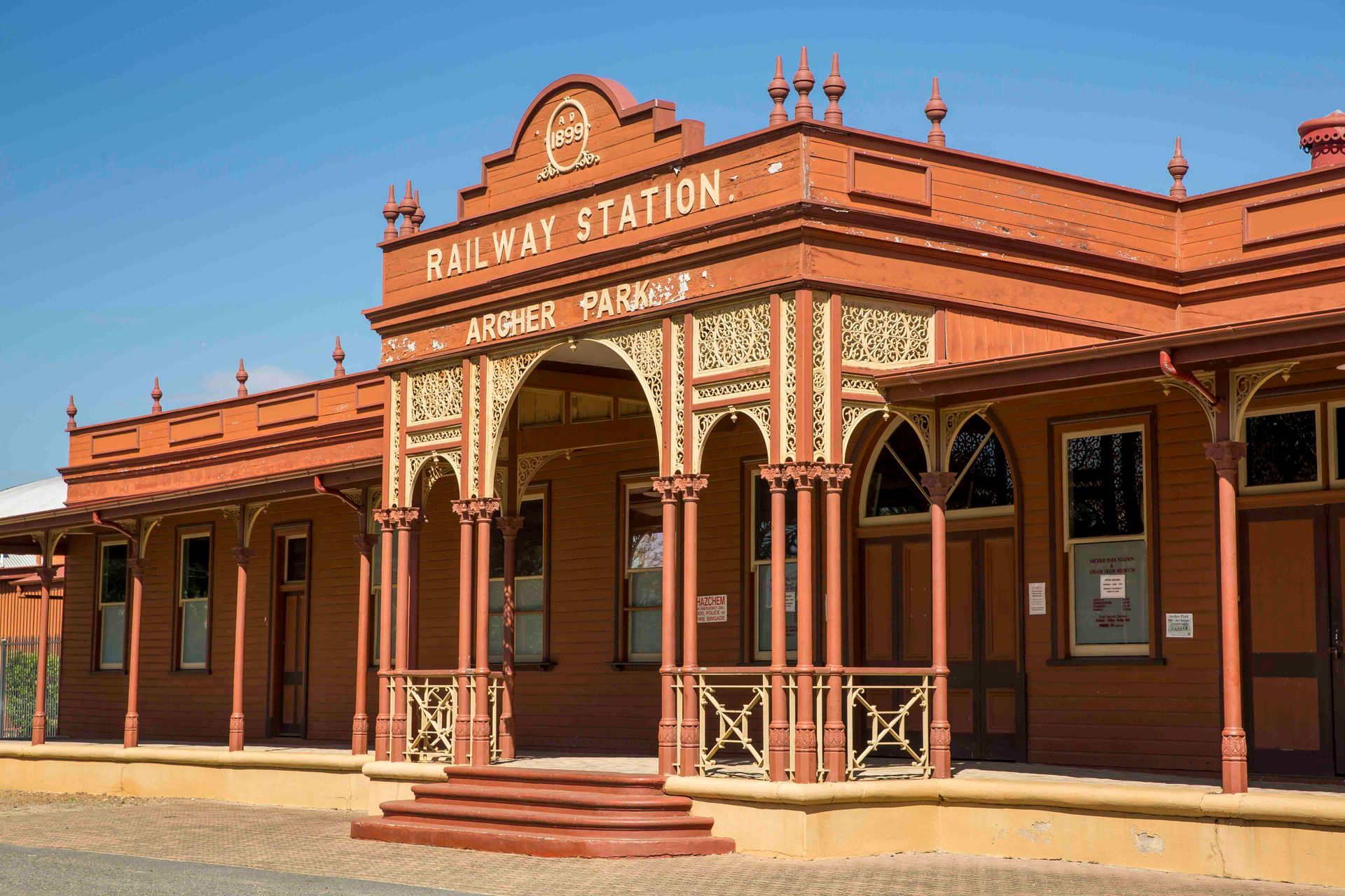 Brown railway station with ornate detailing under a clear, blue sky. Text: Railway Station — HYVIS Plant Hire Pty Ltd in Mulambin, QLD