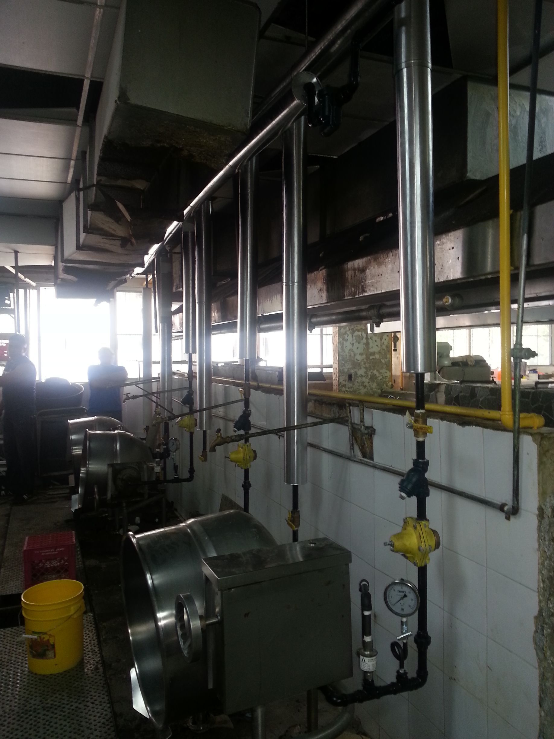 Una habitación con muchas tuberías y un cubo amarillo.