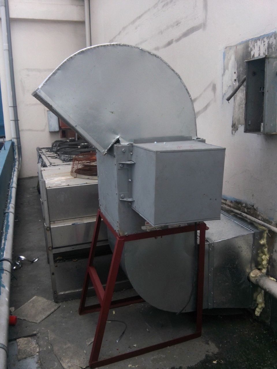 Un gran ventilador de metal está sentado afuera de un edificio.