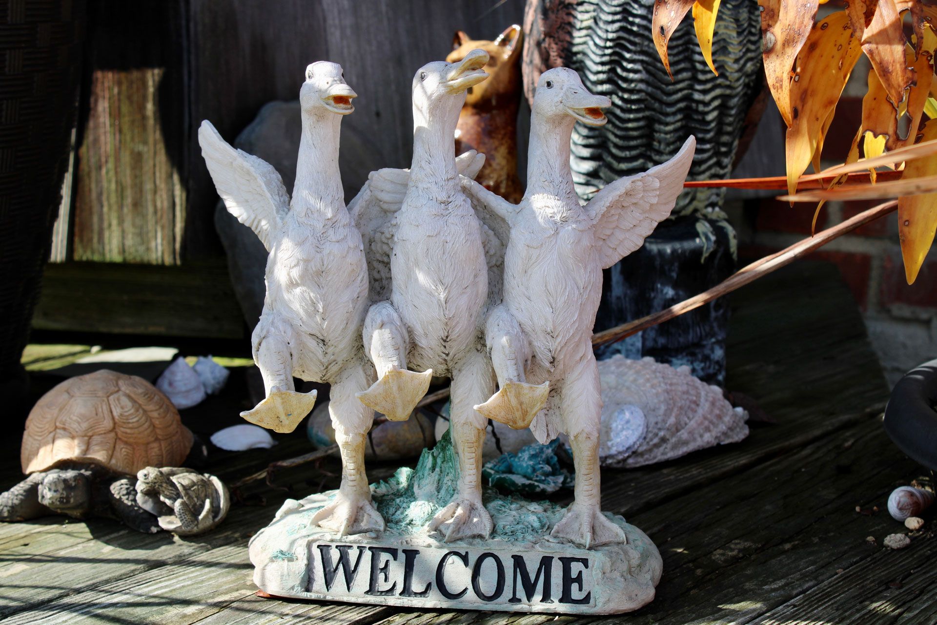 Three white duck statues with wings outstretched, standing on a stone base with 