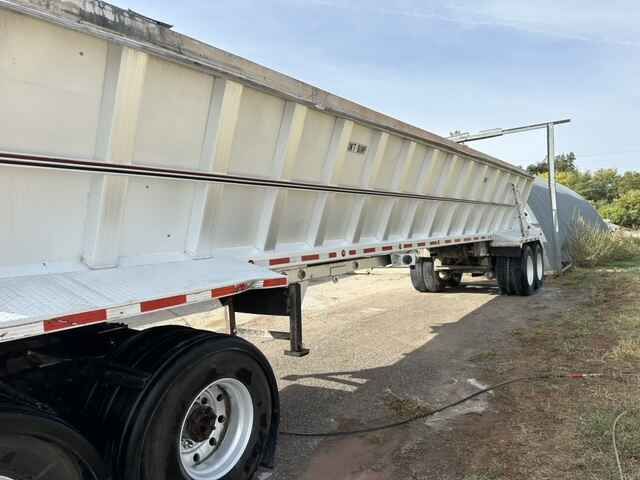 White dump trailer parked outdoors.