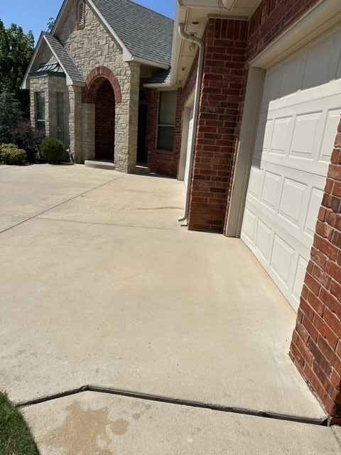 Concrete driveway leading to a house with brick and stone facade, and a white garage door.