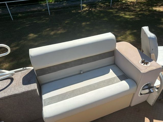 Boat bench with white and gray cushions, a cup holder, and a metal rail.