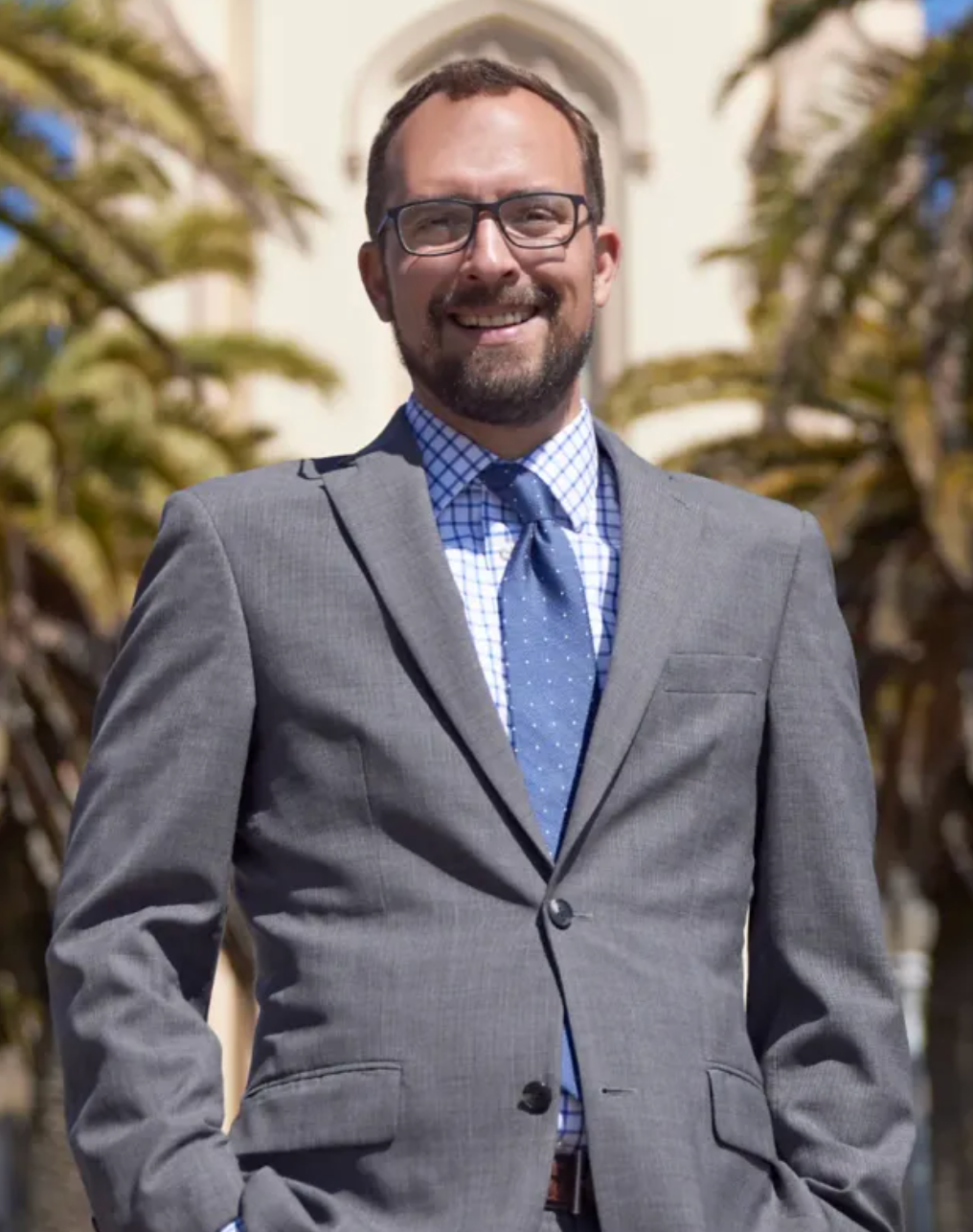 A man in a suit and tie stands with his hands in his pockets